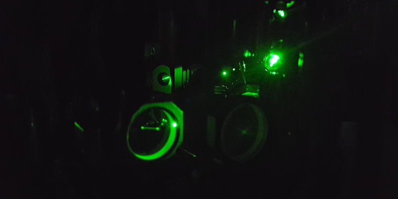 A green laser beam passes through an optical spectroscopy setup